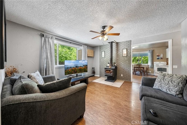 3595 Vista St, Clearlake, CA 95422 - living area with a wood stove, healthy amount of natural light, light wood finished floors, ceiling fan, and a textured ceiling