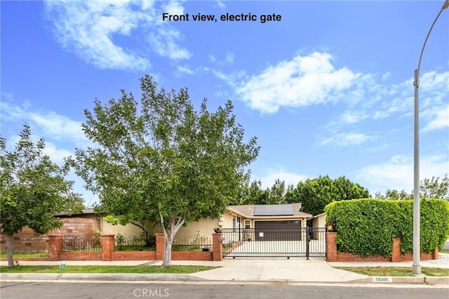 10500 Jordan Ave, Chatsworth, CA 91311 - view of property hidden behind natural elements with roof mounted solar panels, a fenced front yard, a gate, driveway, and brick siding