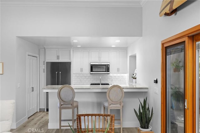 3080 Studio Dr, Cayucos, CA 93430 - kitchen featuring stainless steel microwave, white cabinetry, a peninsula, light wood-style flooring, and recessed lighting