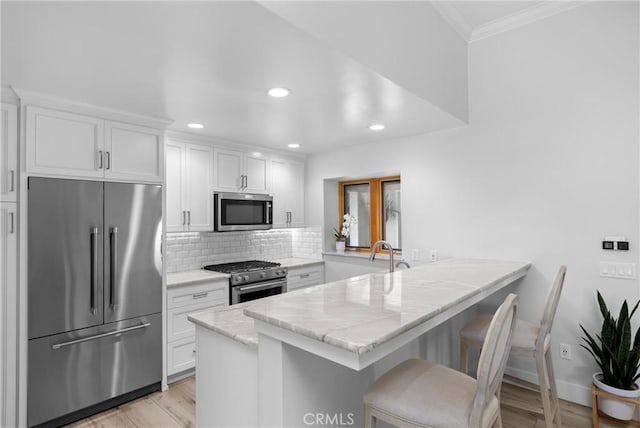 3080 Studio Dr, Cayucos, CA 93430 - kitchen with stainless steel appliances, a peninsula, ornamental molding, white cabinets, and recessed lighting