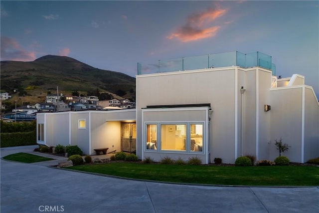 3080 Studio Dr, Cayucos, CA 93430 - back of house at dusk with a mountain view, a lawn, and stucco siding