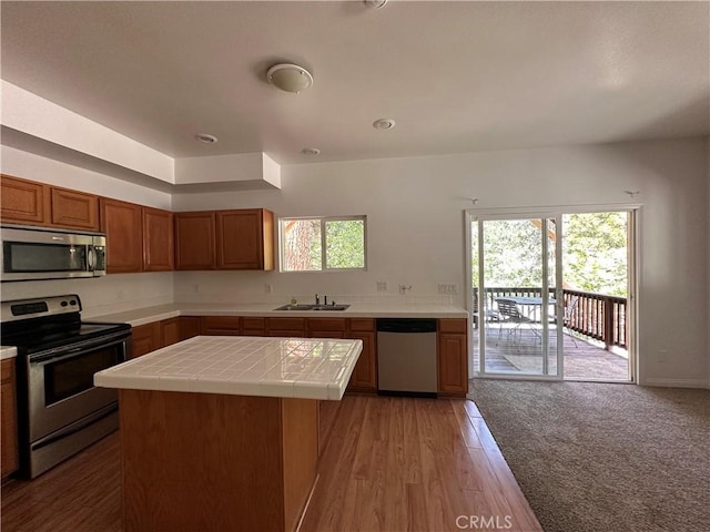 9345 Conifer Dr, Forest Falls, CA 92339 - kitchen featuring stainless steel appliances, tile counters, brown cabinets, a kitchen island, and light wood finished floors