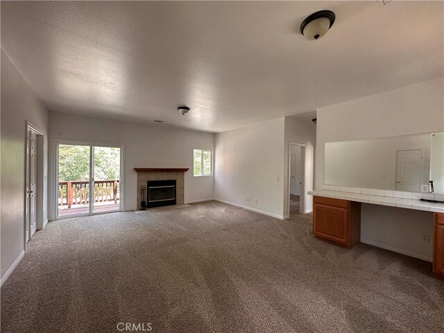 9345 Conifer Dr, Forest Falls, CA 92339 - unfurnished living room with light colored carpet, a tile fireplace, a desk, and a textured ceiling