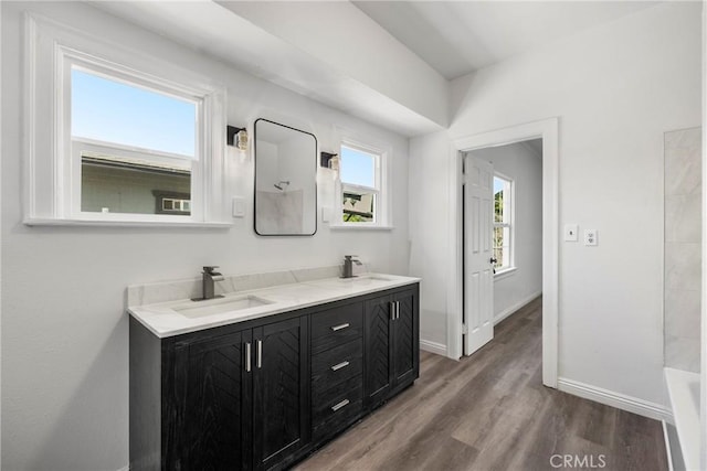 747 W 9th St, San Bernardino, CA 92410 - bathroom with baseboards, wood finished floors, double vanity, and a tub to relax in