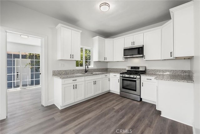 747 W 9th St, San Bernardino, CA 92410 - kitchen with stainless steel appliances, a sink, dark wood finished floors, white cabinets, and light stone counters