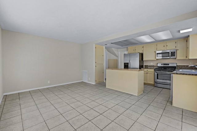 1561 Parkland Way, San Diego, CA 92114 - kitchen featuring stainless steel appliances, dark countertops, a kitchen island, cream cabinets, and light tile patterned floors