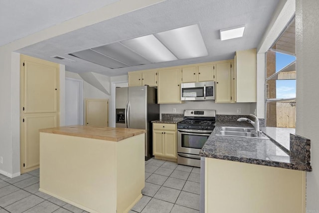 1561 Parkland Way, San Diego, CA 92114 - kitchen with stainless steel appliances, light tile patterned floors, cream cabinets, a kitchen island, and dark stone counters