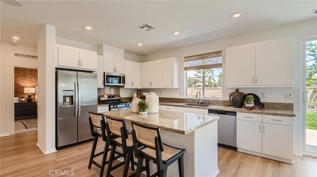 30025 Adrift Ln, Menifee, CA 92584 - kitchen featuring stainless steel appliances, a sink, white cabinetry, light wood-type flooring, and light stone countertops
