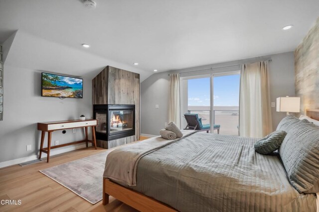 3903 Ocean Dr, Oxnard, CA 93035 - bedroom featuring a multi sided fireplace, access to outside, light wood-type flooring, lofted ceiling, and baseboards