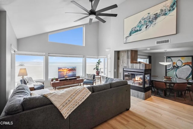 3903 Ocean Dr, Oxnard, CA 93035 - living room featuring a multi sided fireplace, wood finished floors, high vaulted ceiling, and a ceiling fan
