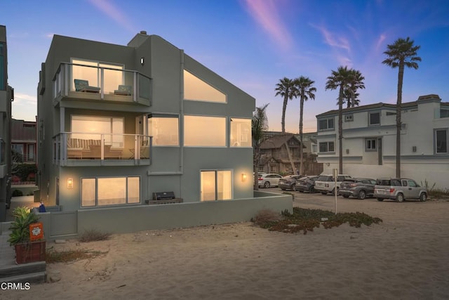 3903 Ocean Dr, Oxnard, CA 93035 - back of house at dusk featuring stucco siding, uncovered parking, and a balcony