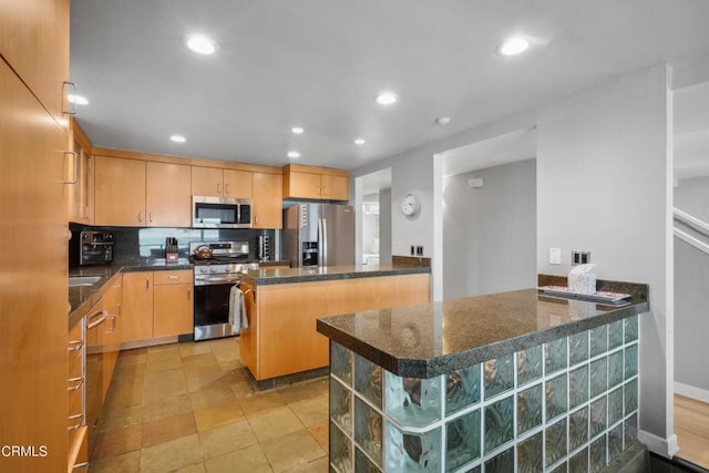 3903 Ocean Dr, Oxnard, CA 93035 - kitchen with stainless steel appliances, a peninsula, recessed lighting, backsplash, and dark stone counters