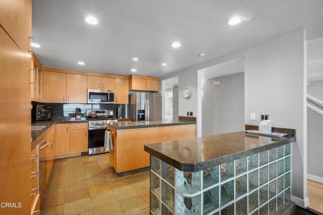 3903 Ocean Dr, Oxnard, CA 93035 - kitchen featuring stainless steel appliances, a peninsula, recessed lighting, decorative backsplash, and dark stone counters