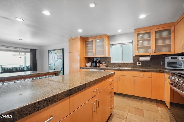 3903 Ocean Dr, Oxnard, CA 93035 - kitchen featuring gas stove, decorative backsplash, recessed lighting, glass insert cabinets, and pendant lighting