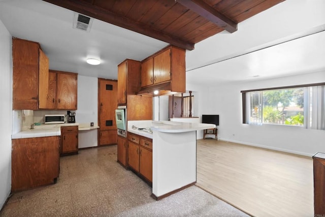 1520 Flanagan St, Pomona, CA 91766 - kitchen with white microwave, wall oven, brown cabinetry, light floors, and beam ceiling