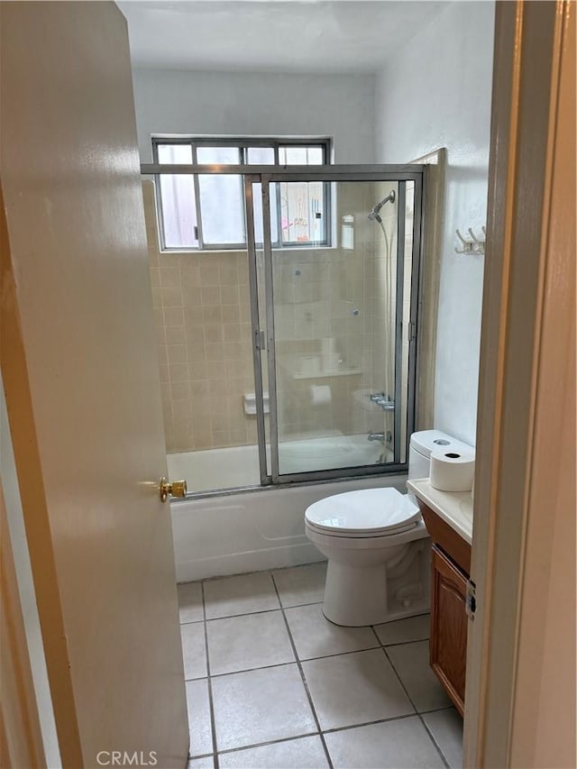 bathroom with tile patterned flooring, bath / shower combo with glass door, toilet, and vanity
