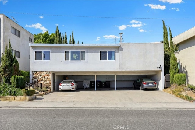 townhome / multi-family property with stucco siding, a carport, stone siding, and concrete driveway