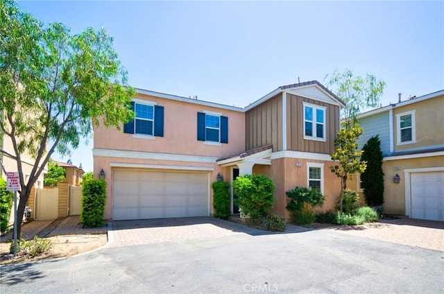 2910 E Via Terrano, Ontario, CA 91764 - view of property featuring decorative driveway, a garage, board and batten siding, stucco siding, and fence