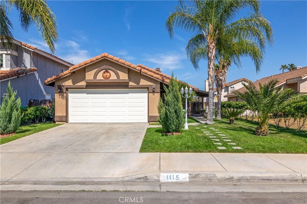 1115 White Tip Ln, Perris, CA 92571 - view of front of property with stucco siding, an attached garage, a front lawn, and driveway