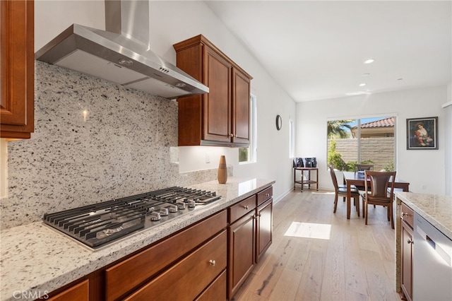 27 Medoc, Rancho Mirage, CA 92270 - kitchen with wall chimney exhaust hood, appliances with stainless steel finishes, backsplash, light wood finished floors, and light stone countertops
