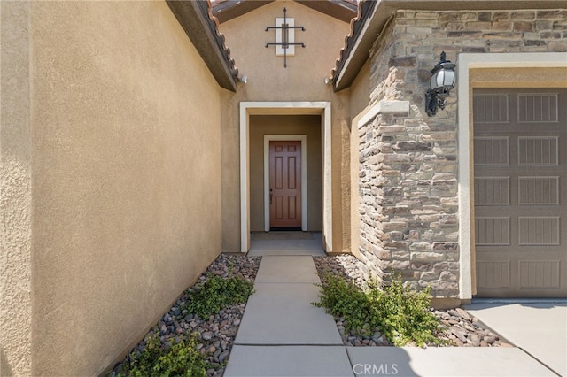 27 Medoc, Rancho Mirage, CA 92270 - doorway to property featuring stone siding, stucco siding, and an attached garage