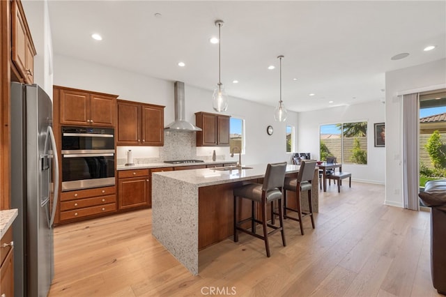 27 Medoc, Rancho Mirage, CA 92270 - kitchen with appliances with stainless steel finishes, wall chimney range hood, a sink, light wood-style flooring, and recessed lighting