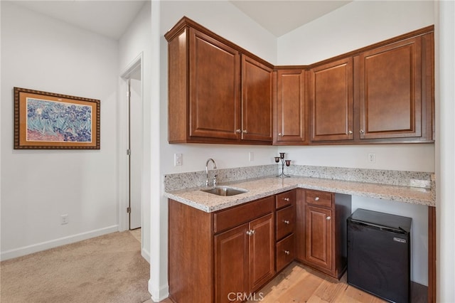 27 Medoc, Rancho Mirage, CA 92270 - kitchen featuring a sink, light stone counters, baseboards, and brown cabinetry