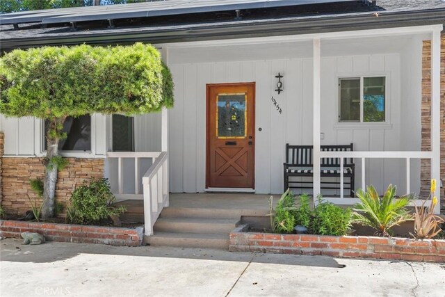 6454 Baird Ave, Reseda, CA 91335 - view of exterior entry featuring a porch, board and batten siding, and roof mounted solar panels