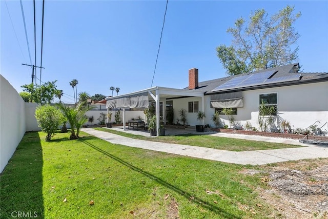 6454 Baird Ave, Reseda, CA 91335 - rear view of property with roof mounted solar panels, a patio, stucco siding, and a chimney