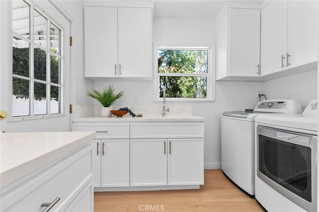 6454 Baird Ave, Reseda, CA 91335 - clothes washing area with washing machine and dryer, cabinet space, and light wood-type flooring