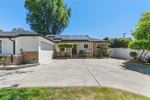 6454 Baird Ave, Reseda, CA 91335 - ranch-style home with a porch, an attached garage, roof mounted solar panels, driveway, and fence