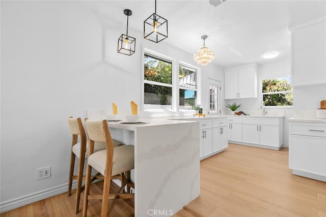 6454 Baird Ave, Reseda, CA 91335 - kitchen with a kitchen breakfast bar, white cabinets, light wood finished floors, pendant lighting, and a peninsula