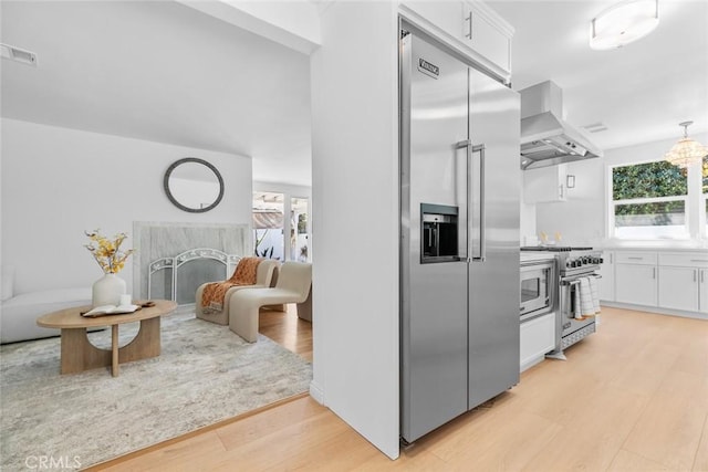 6454 Baird Ave, Reseda, CA 91335 - kitchen with built in appliances, white cabinetry, light wood finished floors, and wall chimney exhaust hood