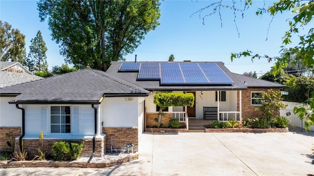 6454 Baird Ave, Reseda, CA 91335 - ranch-style home with covered porch, stone siding, roof mounted solar panels, and a shingled roof