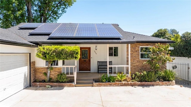 6454 Baird Ave, Reseda, CA 91335 - view of front facade featuring a porch, a shingled roof, roof mounted solar panels, driveway, and stone siding