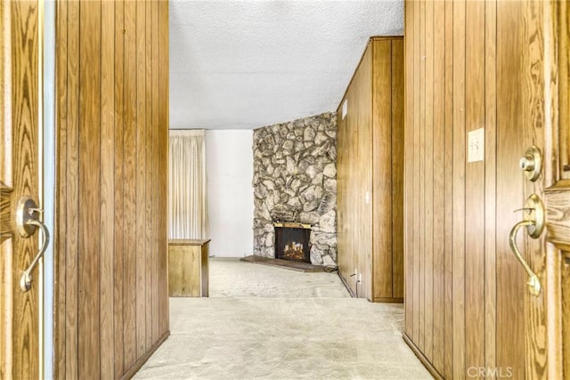 hall featuring carpet, a textured ceiling, and wood walls