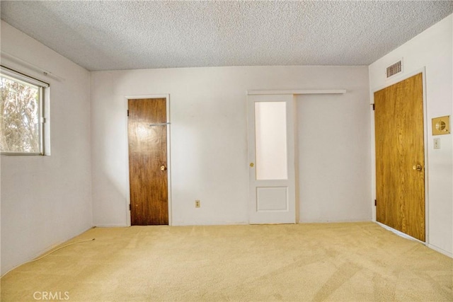 carpeted empty room with a textured ceiling