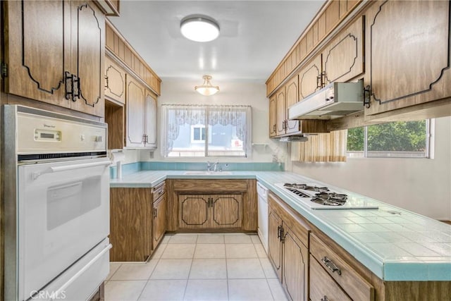 kitchen with under cabinet range hood, white appliances, healthy amount of natural light, and a warming drawer