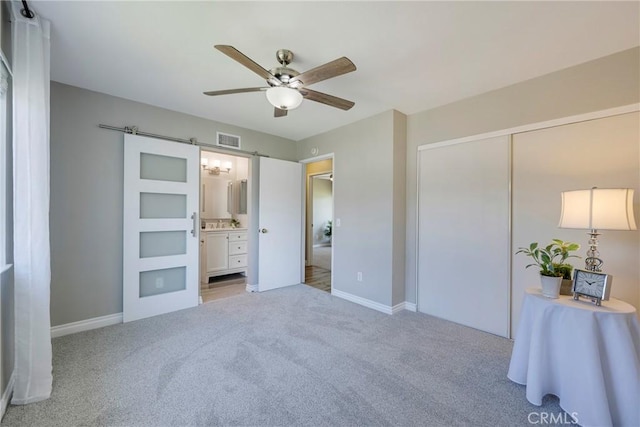 unfurnished bedroom with light carpet, baseboards, ensuite bathroom, and ceiling fan
