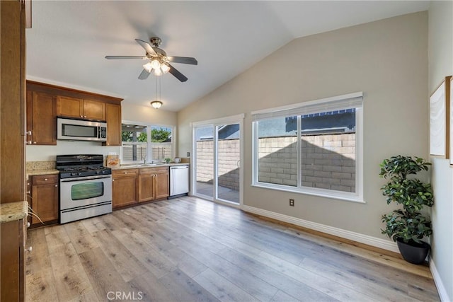 kitchen featuring stainless steel appliances, brown cabinetry, ceiling fan, lofted ceiling, and light wood-type flooring