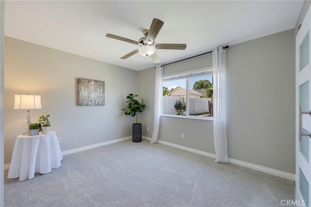 carpeted spare room featuring a ceiling fan and baseboards