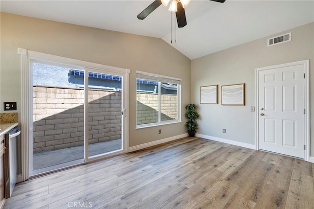 empty room with lofted ceiling, light wood-style floors, ceiling fan, healthy amount of natural light, and baseboards