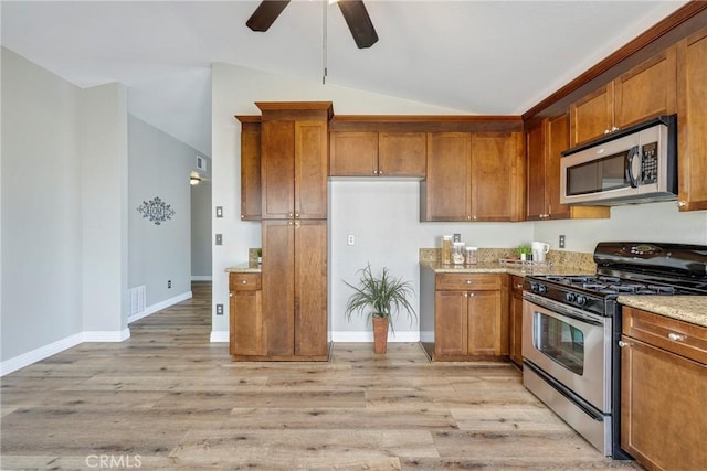 kitchen featuring stainless steel appliances, lofted ceiling, ceiling fan, brown cabinets, and light stone counters