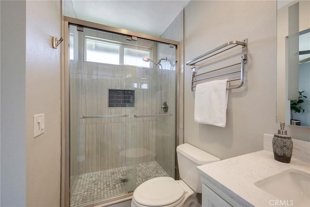 full bathroom with toilet, a shower stall, vanity, and a textured wall