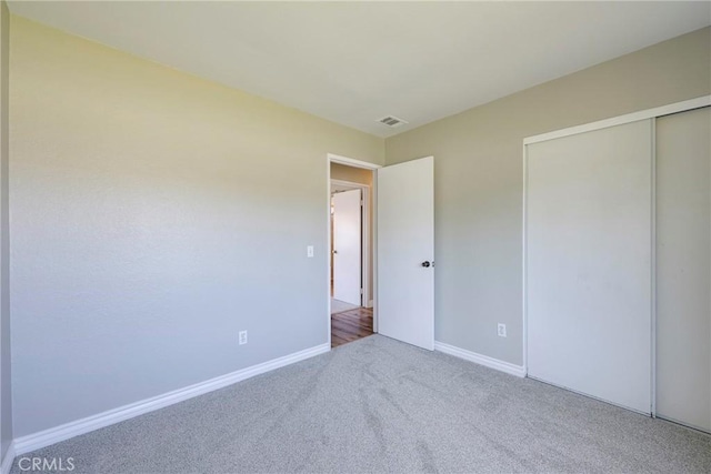 unfurnished bedroom featuring carpet flooring, baseboards, and a closet