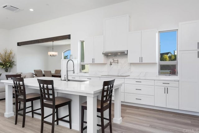 239 Futurity Ln, Fallbrook, CA 92028 - kitchen with white cabinetry, light wood-type flooring, decorative backsplash, a kitchen breakfast bar, and recessed lighting