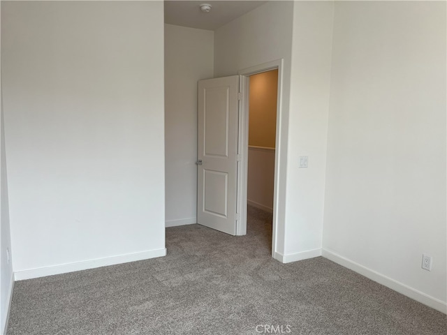 unfurnished room featuring carpet, baseboards, and a smoke detector