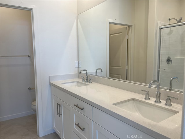 bathroom featuring toilet, a stall shower, double vanity, tile patterned floors, and baseboards