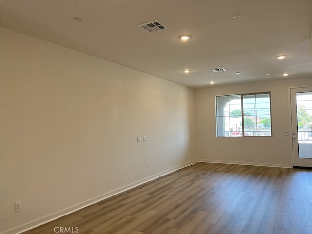 spare room with wood finished floors, baseboards, and recessed lighting