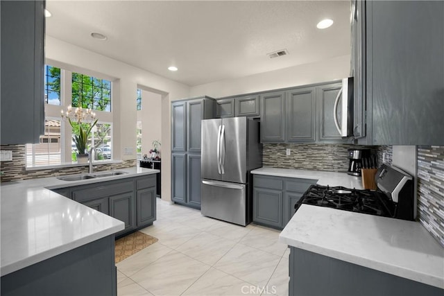kitchen featuring appliances with stainless steel finishes, a sink, decorative backsplash, light countertops, and recessed lighting